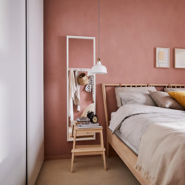 Chambre à coucher avec une armoire IKEA PAX blanche avec un tabouret utilisé comme table de chevet.