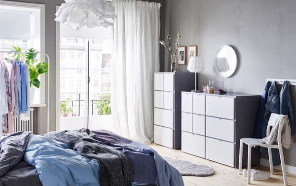 Chambre à coucher en bleu, gris et blanc, meublée de deux commodes IKEA VISTHUS blanches côte à côte.