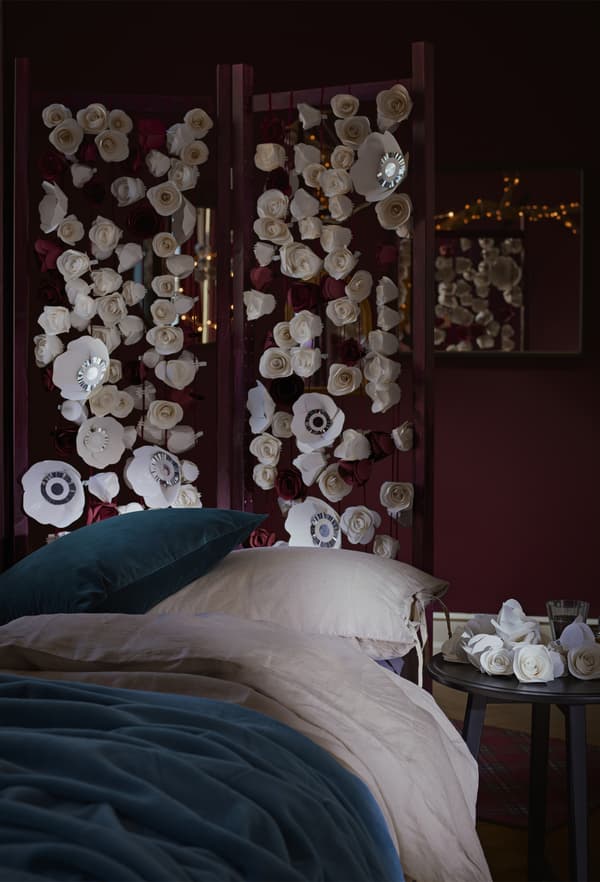Chambre à coucher rouge foncé avec lit habillé de linge bleu et blanc et paravent à motif floral.