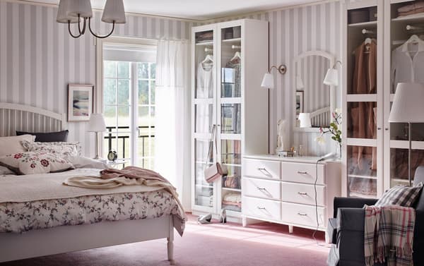 Chambre à coucher traditionnelle avec papier peint rayé gris et blanc, sol rose et garde-robes PAX blanches avec portes TYSSEDAL en verre.
