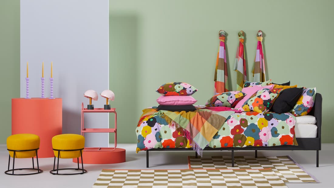 Chambre avec draps colorés avec motifs floraux, tabourets jaunes, draps accrochés aux murs