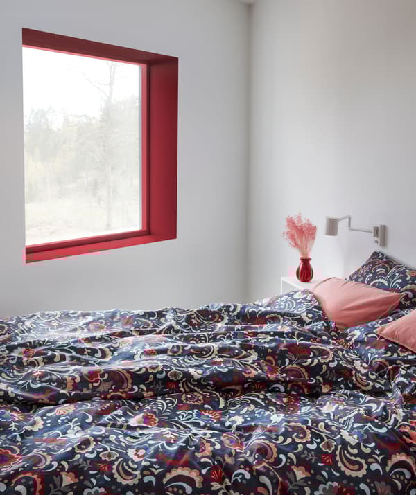 Chambre avec lit recouvert d’un linge de lit aux couleurs vives, avec motif traditionnel suédois en 