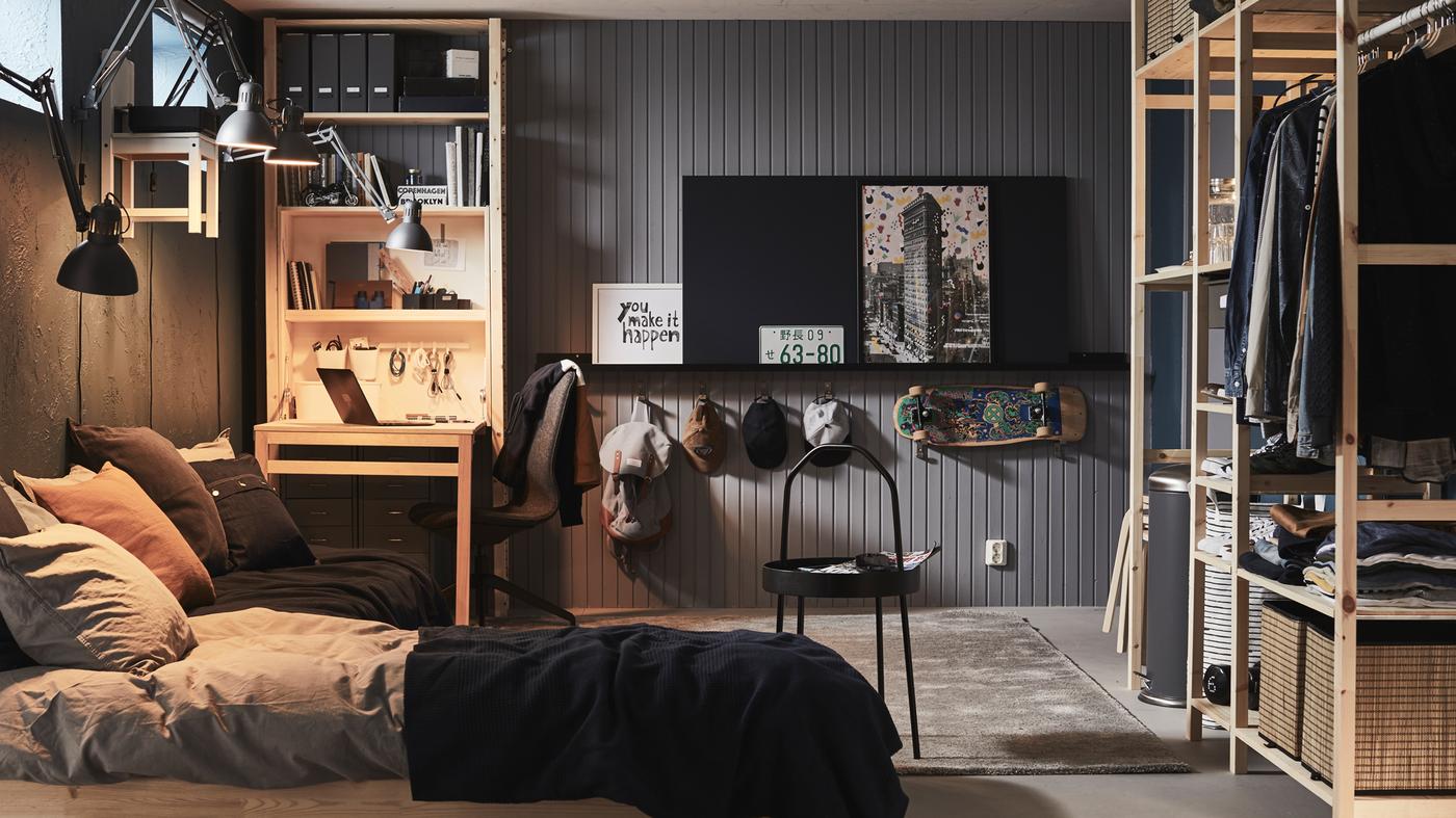 Chambre avec un lit et des rangements sous la forme de grandes étagères IVAR et d’un rangement avec table pliante IVAR.