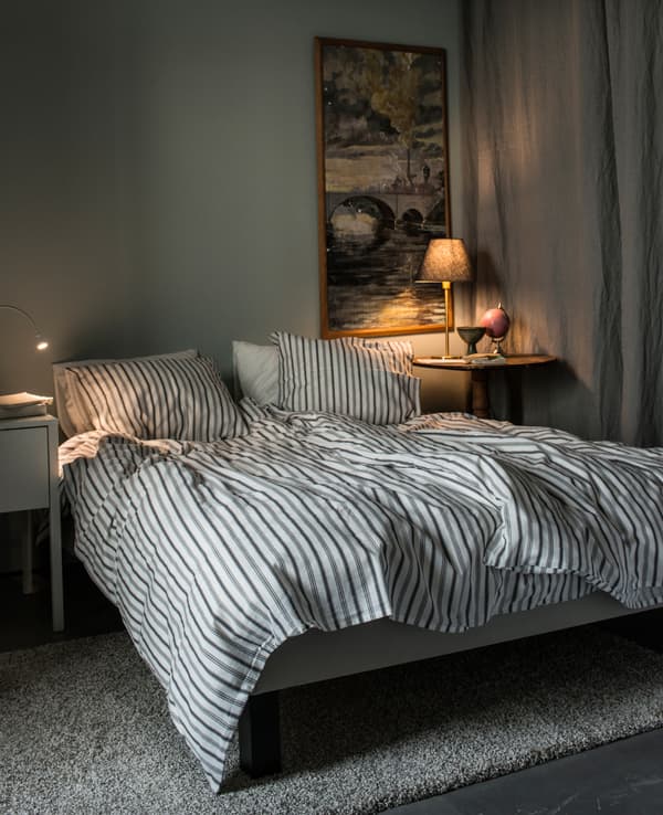 Chambre dans des couleurs claires, avec lit et deux tables de chevet.