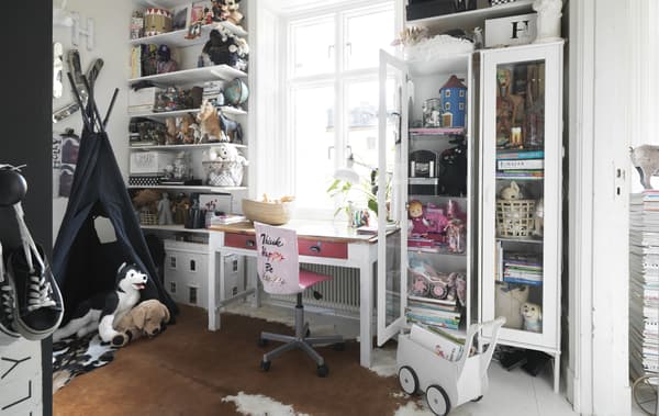 Chambre d’enfant avec rangement ouvert et chaise rose.