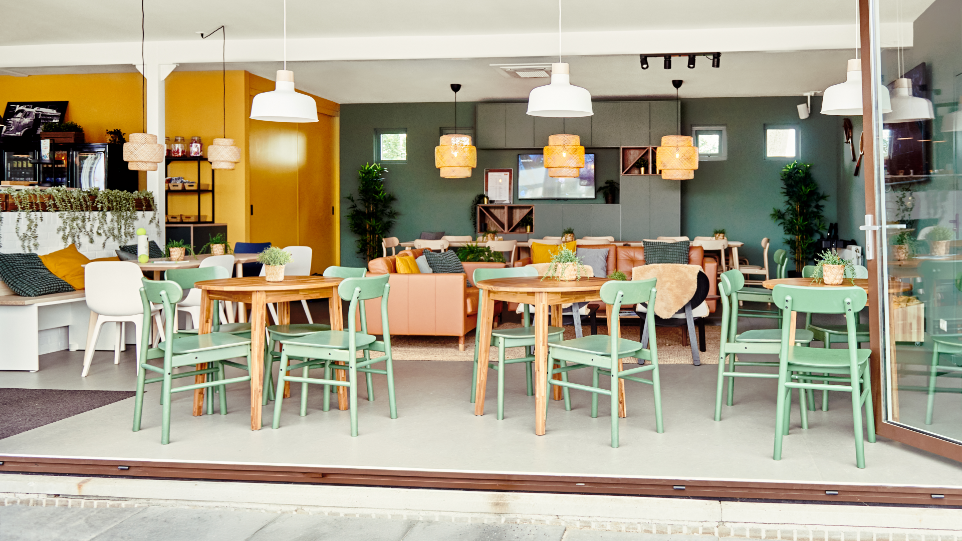 Cheerful canteen with wooden tables, green chairs and benches.