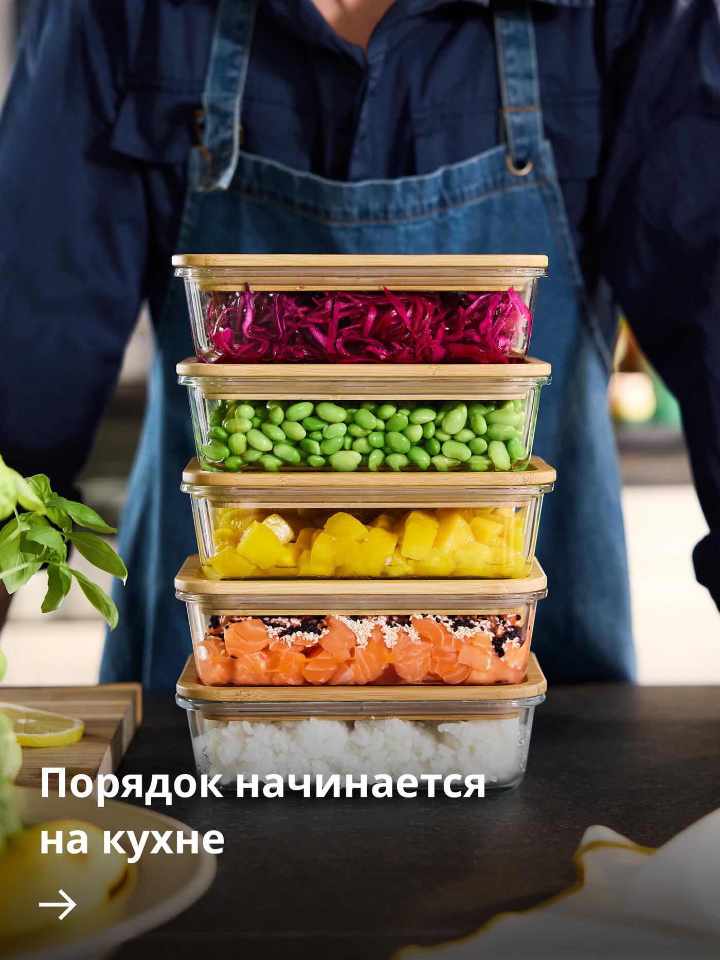 Человек стоит рядом со стопкой разноцветных контейнеров для хранения продуктов IKEA 365+, наполненных различными ингредиентами и готовыми блюдами.