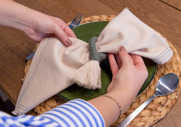Chica acomodando una servilleta de tela en un porta servilletas.