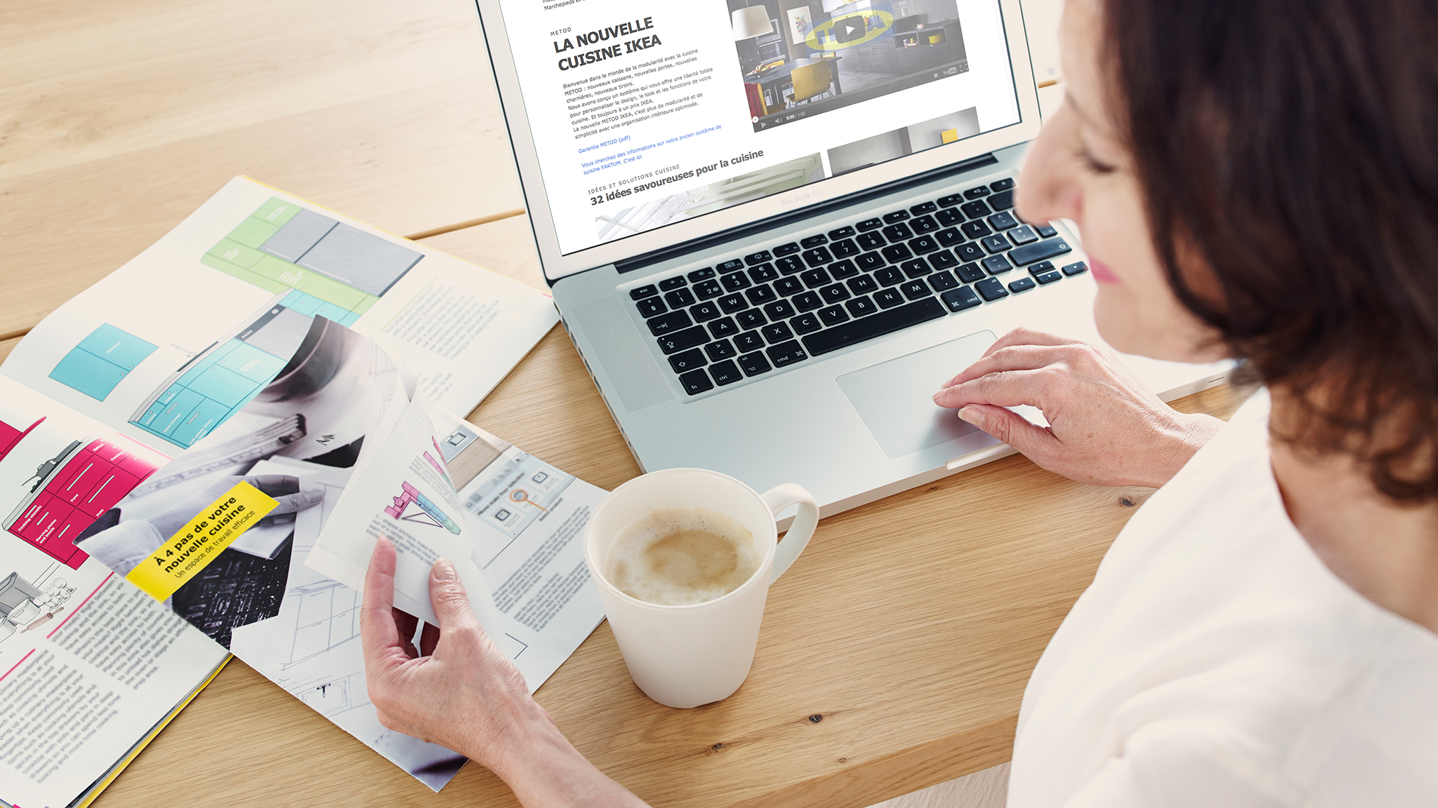 Chica revisando revistas informativas, tomando una taza de café mientras checa su laptop