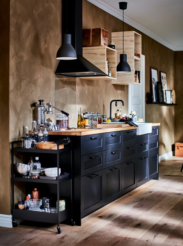 Chicinetă utilată complet, cu corpuri de perete deschise de dimensiuni reduse, hotă și fețe de sertare LERHYTTAN de culoare închisă.