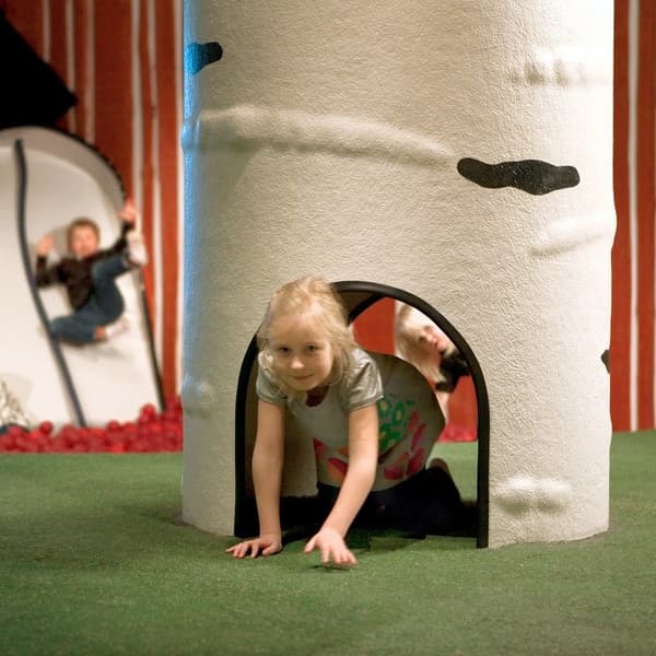 Child crawling through a white birch tree-shaped play structure with a circular opening at the base.