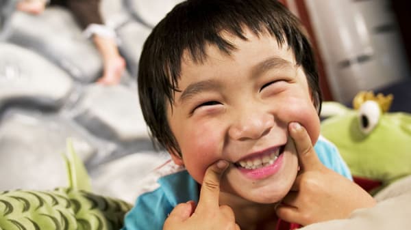 Child smiling at camera while other kids play in the IKEA Smaland in the background