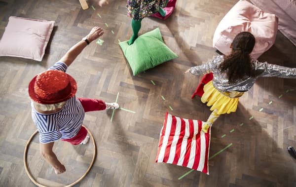 Children and adults playing a game with cushions on the floor.