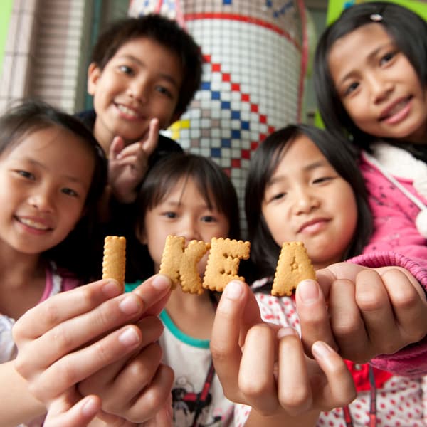 Children holding up alphabet-shaped biscuits that spell out IKEA.