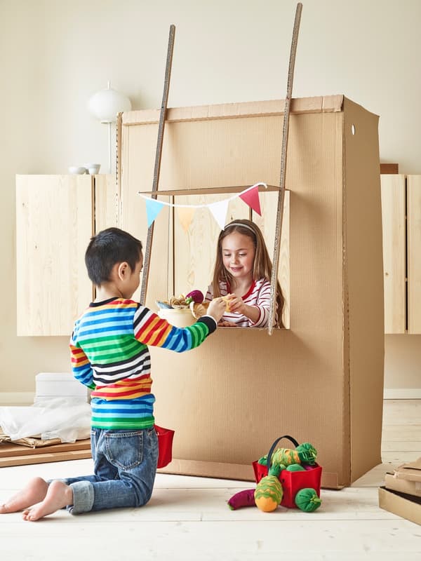 Children playing with a cardboard market stall.