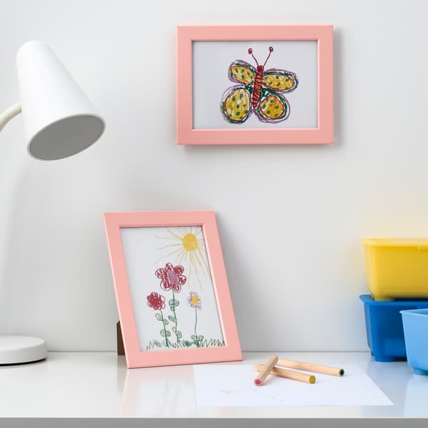 Children's drawings in pink frames on a white wall