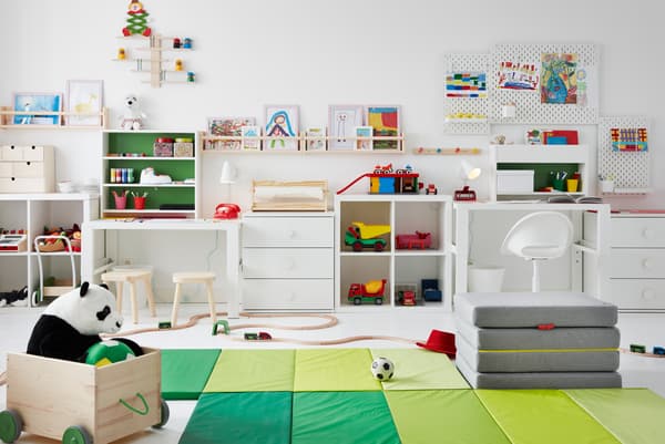 Children’s room with toys across the floor, desks along the side, and drawings on pegboards and FLISAT ledges up the walls.