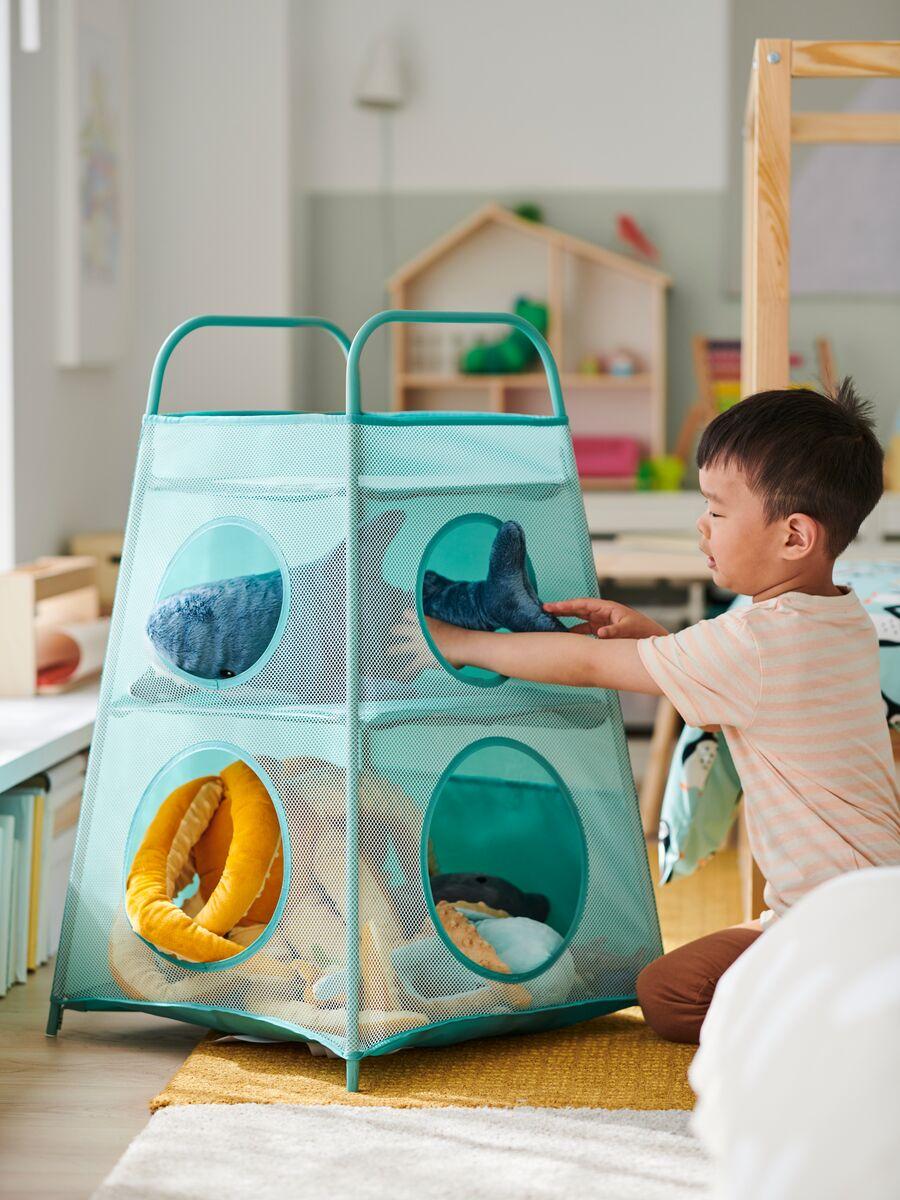 Children’s storage
Child playing with a green and blue mesh storage organizer filled with soft toys and books.