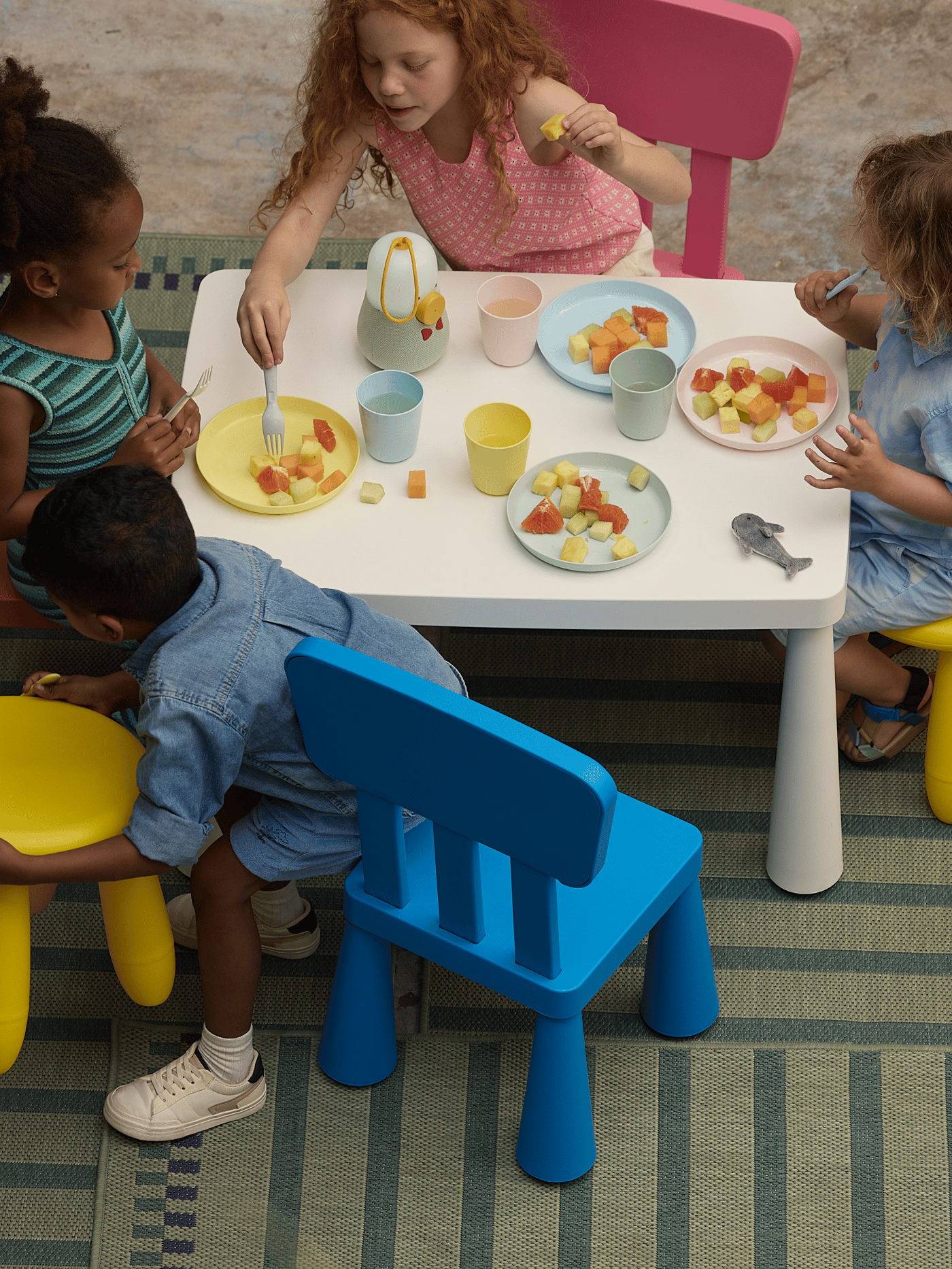 Children’s tableware and kitchenware
Children sitting around a white table with colorful toy food and play kitchenware, engaging in pretend play.