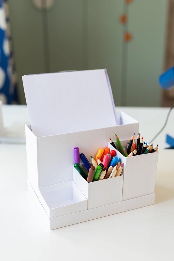 Чёрная перфорированная панель, закреплённая на синей стене над письменным столом