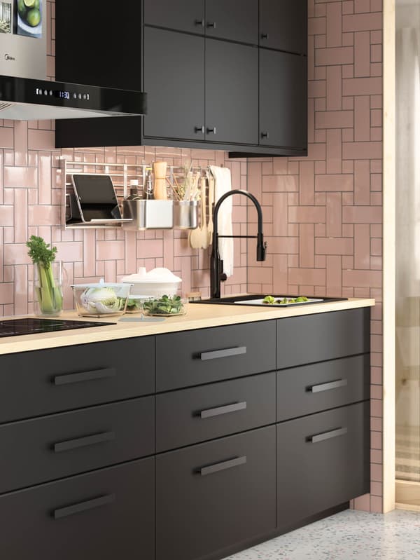 Čierna kuchynská linka KUNGSBACKA s pracovnou doskou zo svetlého dreva, čiernym drezom a čiernou kuchynskou batériou TOLLSJÖN.