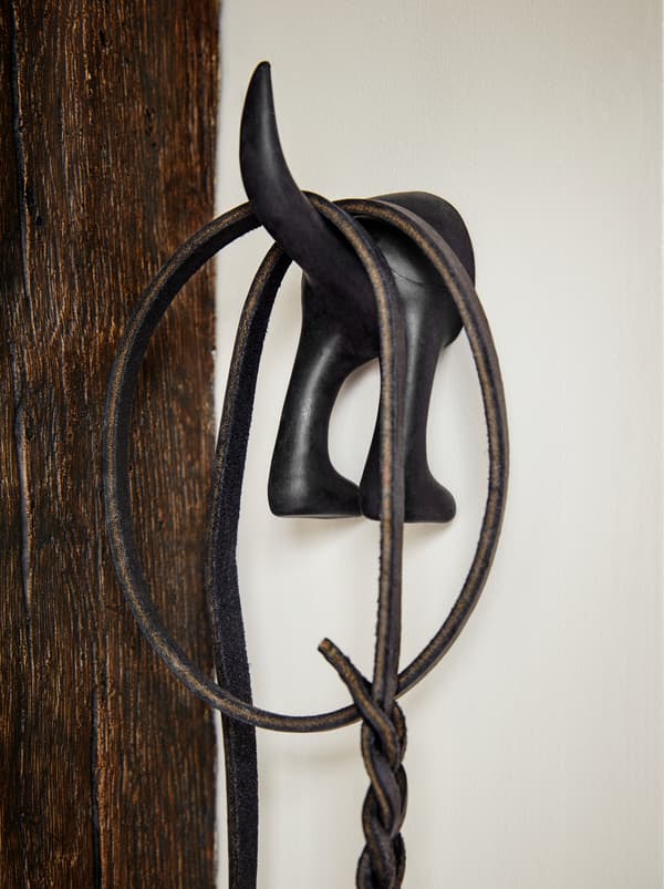 Čierny vešiak BÄSTIS v tvare psa s chvostom, na ktorom je zavesená vôdzka pre psa. 