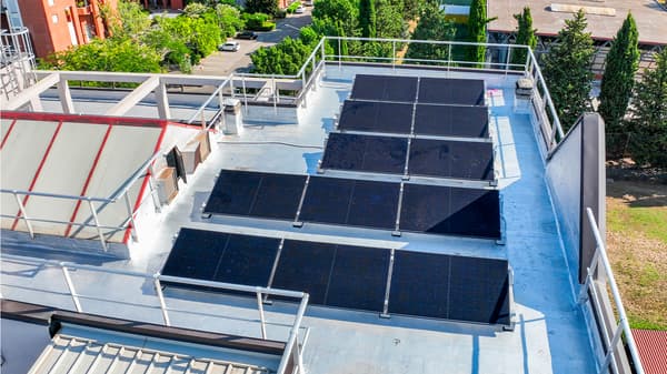 Cinque file di pannelli fotovoltaici installati sulla terrazza di un condominio. 