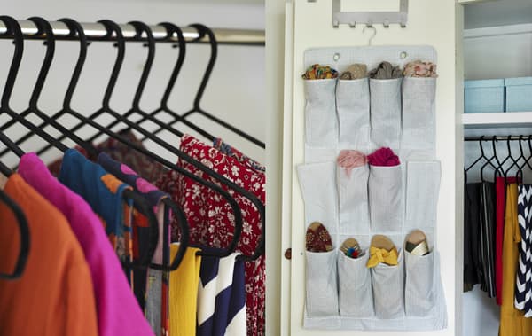 Cintres noirs dans une armoire remplie de vêtements colorés et accessoires rangés dans un organiseur à chaussures garnissant l’intérieur de la porte d’une armoire.