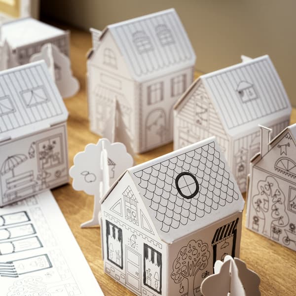 Città di cartone MÅLA con case e alberi, su una superficie in legno.