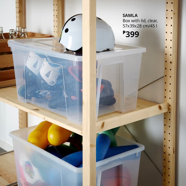 Clear SAMLA storage boxes on a wooden shelving unit hold helmets and colorful toys; a sign lists the box size and ₱399 price, creating a practical IKEA store display.