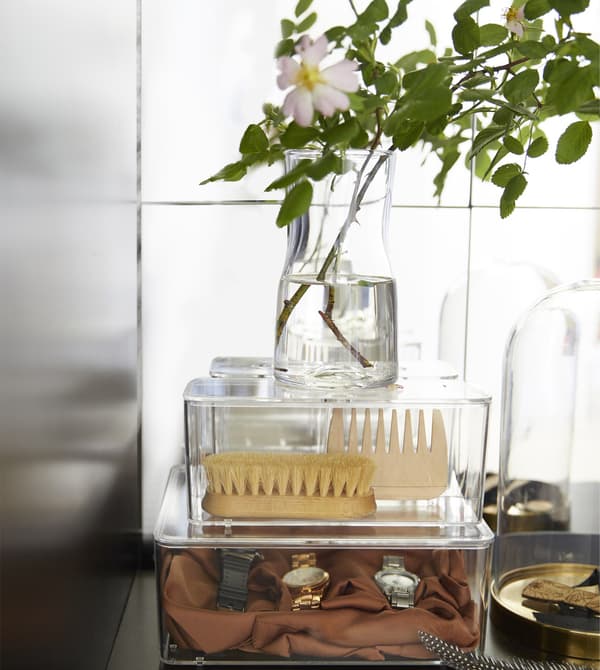Clear storage boxes organise personal grooming items on a bedroom vanity.