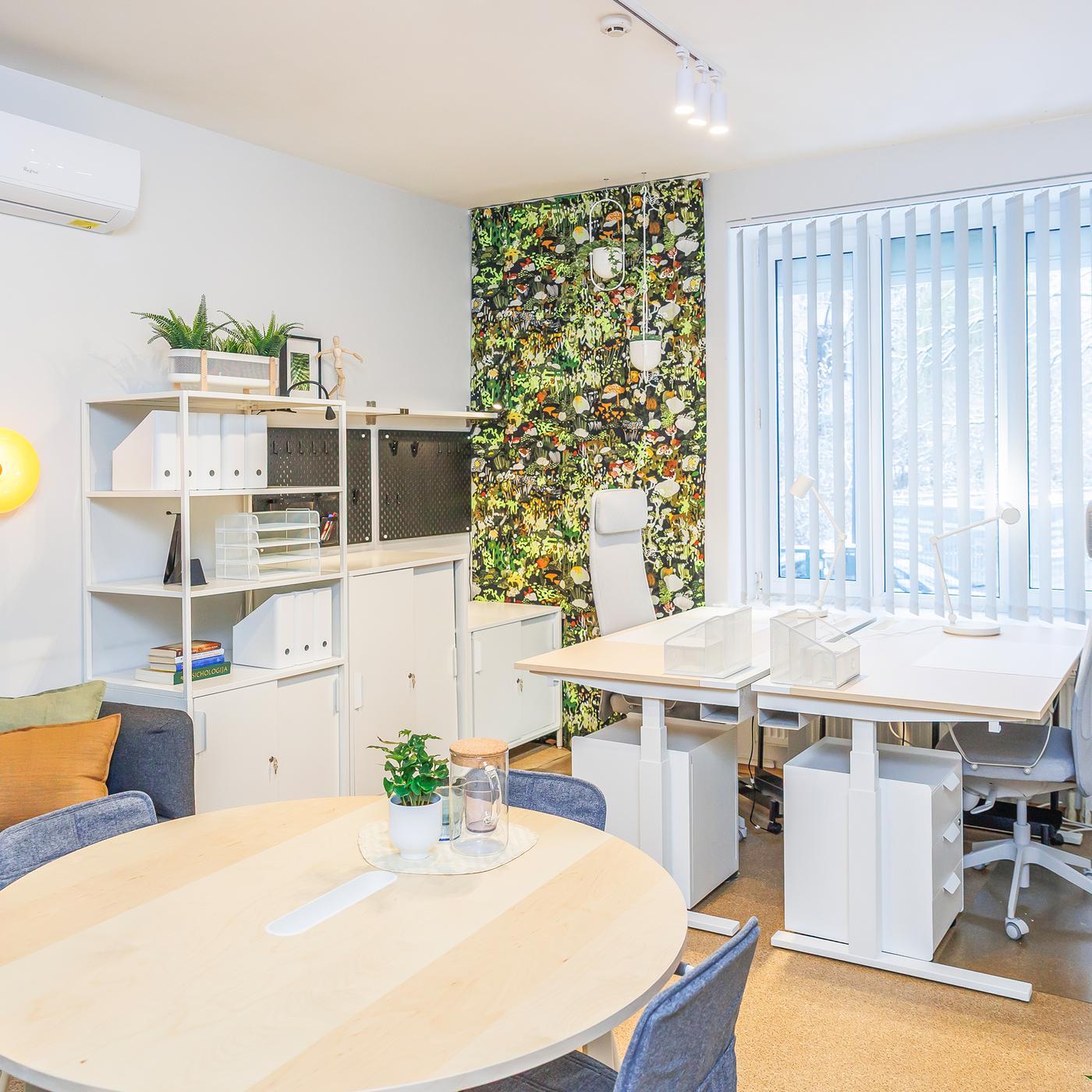 Clearly defined zones in the reception area: a round table for meetings with visitors in the centre of the room and workstations for staff by the window.