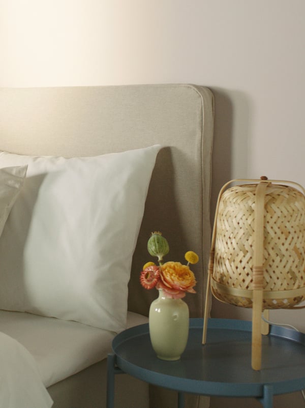 Close-up of a bed, a pillow and a nightstand with a lamp.
