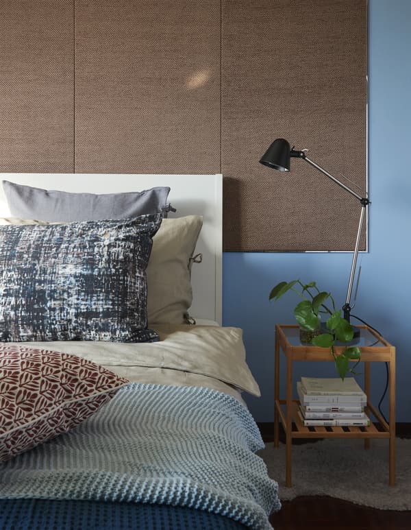 Close-up of a bed and bedside table against a blue wall.