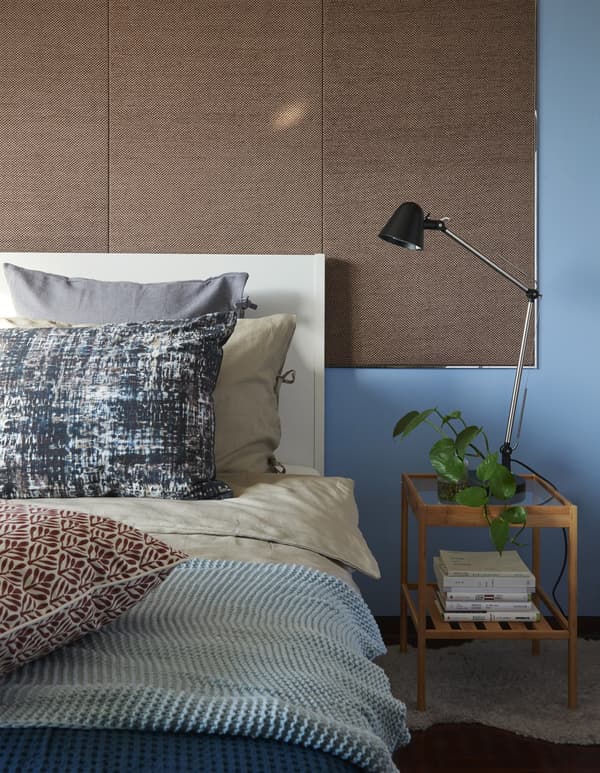 Close-up of a bed and bedside table against a blue wall.