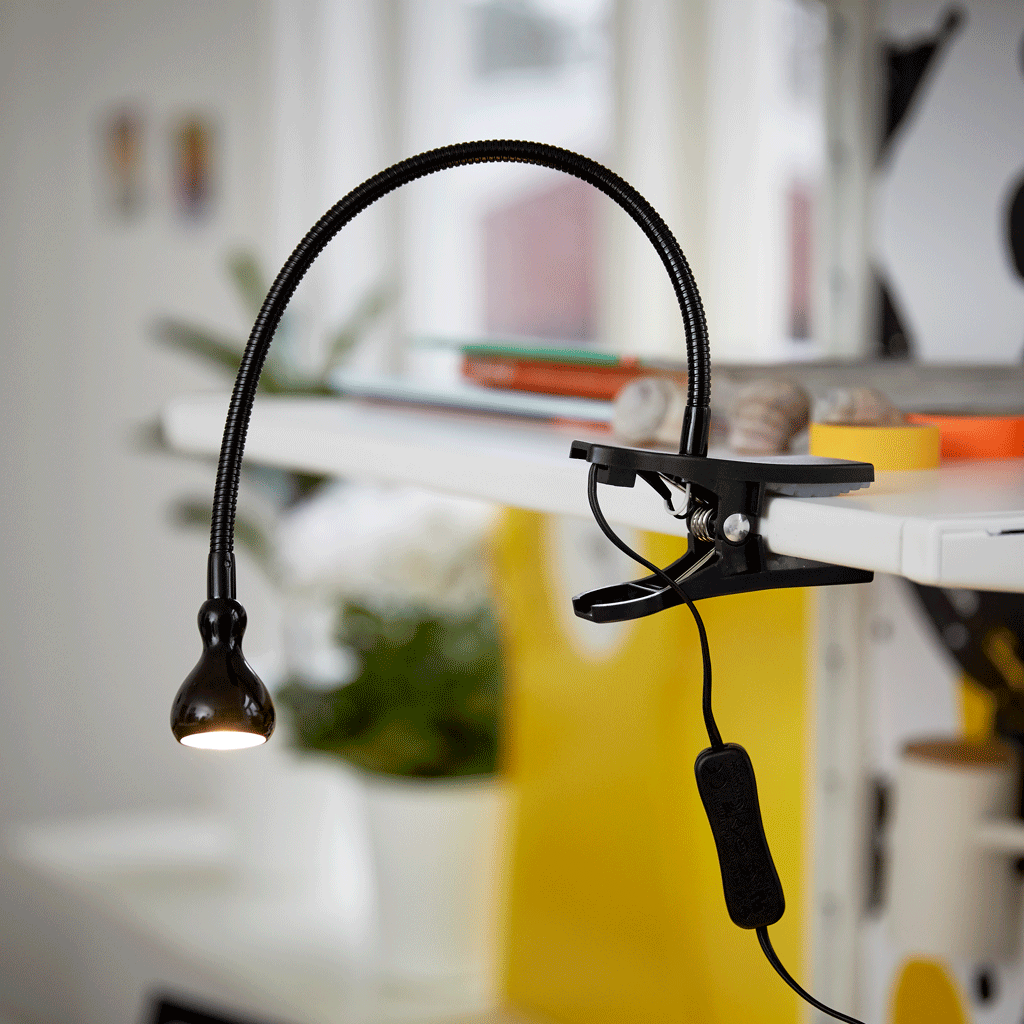 Close-up of a black clamp spotlight attached to a shelf.