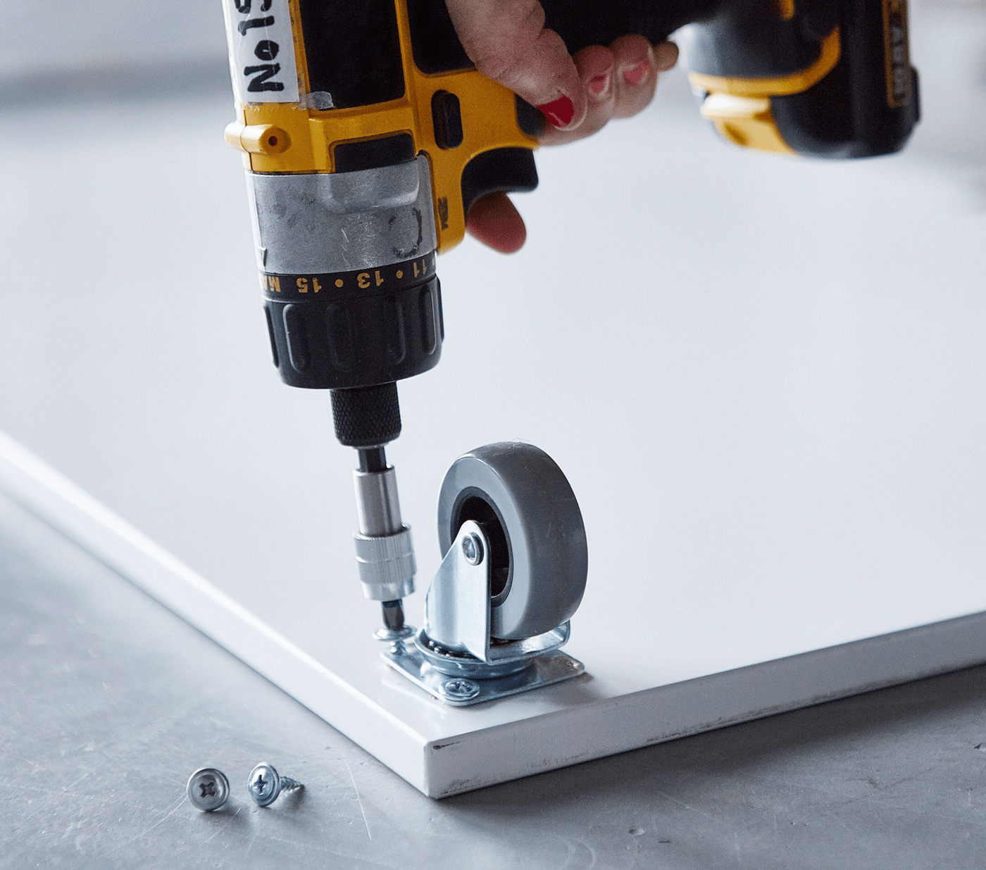 Close-up of a castor being attached to a board.