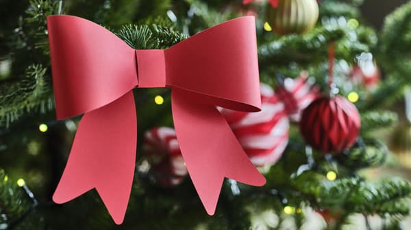 Close-up of a decorated Christmas tree with bright red paper bows and red and gold ornaments.