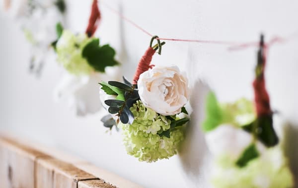 Close-up of a floral garland on a white wall.
