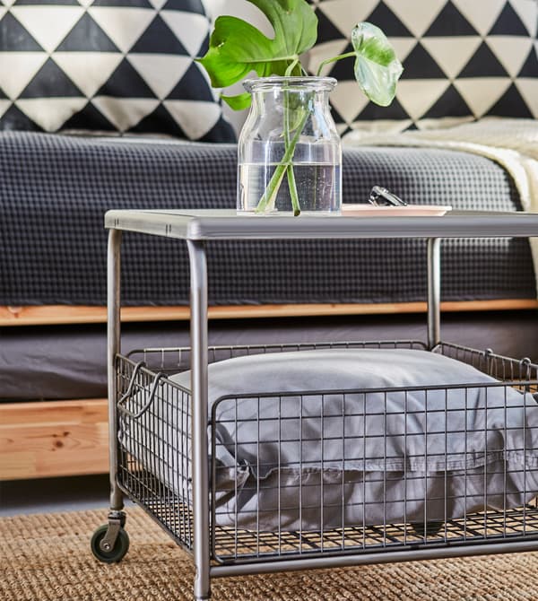 Close-up of a grey steel coffee table with a wire mesh basket underneath.
