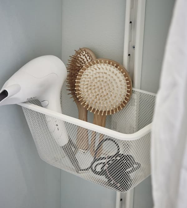 Close-up of a hair drier and different brushes stored in ALGOT white mesh basket.