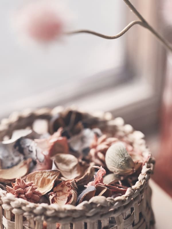 Close-up of a hand-braided VÅRDANDE basket, made from banana fiber and filled with potpourri.