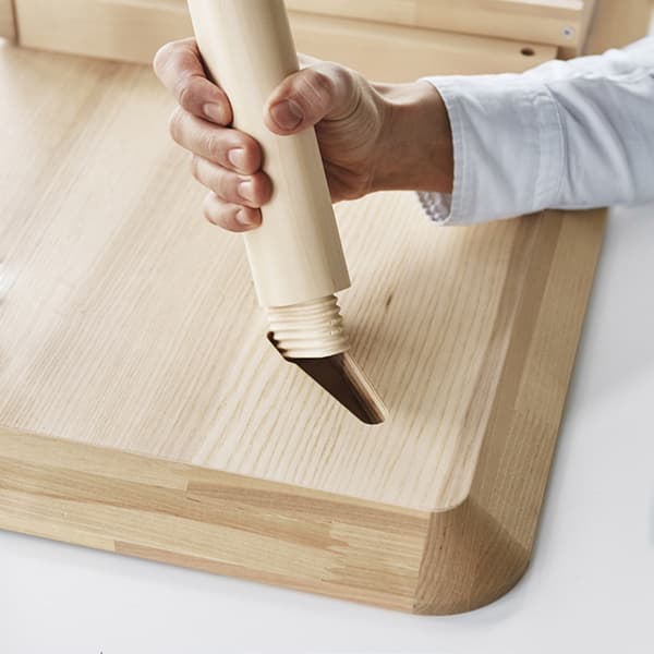Close up of a hand holding the leg of a table and trying to attach it to a table top