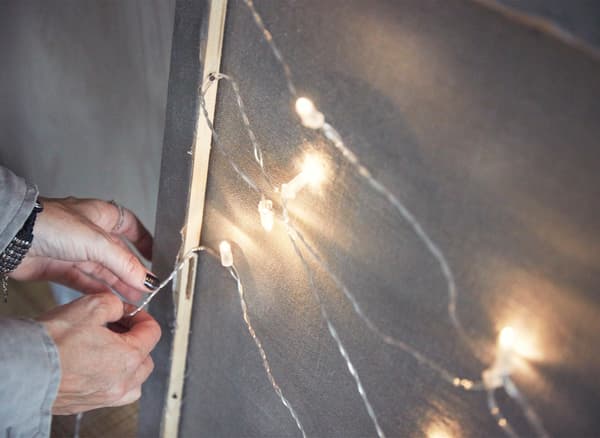 Close-up of a light chain being attached to the back of a canvas frame.