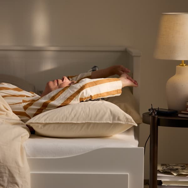 Close-up of a woman in striped pajamas sleeping tight in HEMNES day-bed.