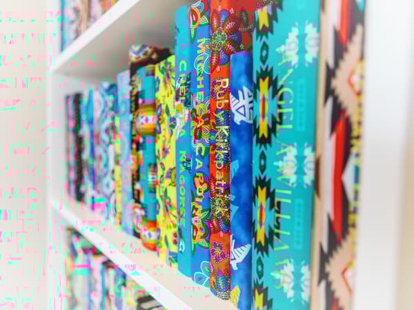 Close up of BILLY bookcase shelf of fabric wrapped books with gold names printed on spine.