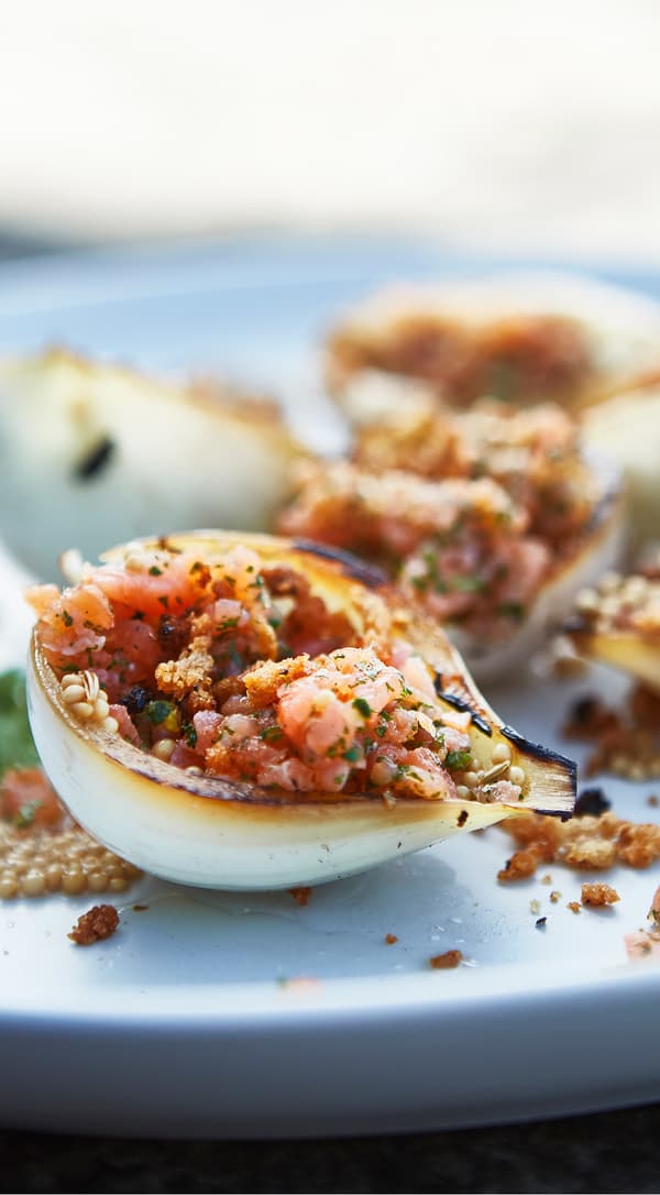 Close-up of cold-smoked salmon tartar in scorched half onions.