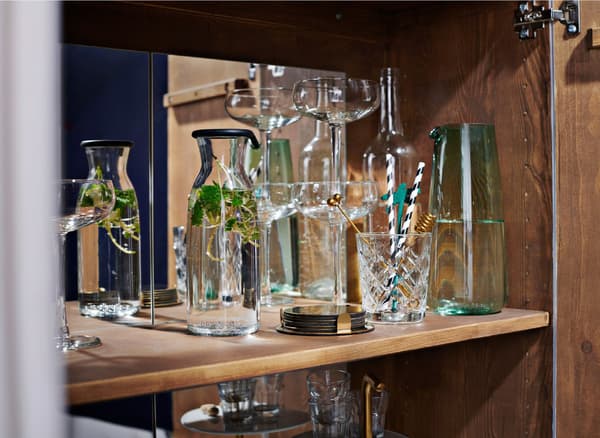 Close-up of drinking glasses and a carafe inside a cabinet.