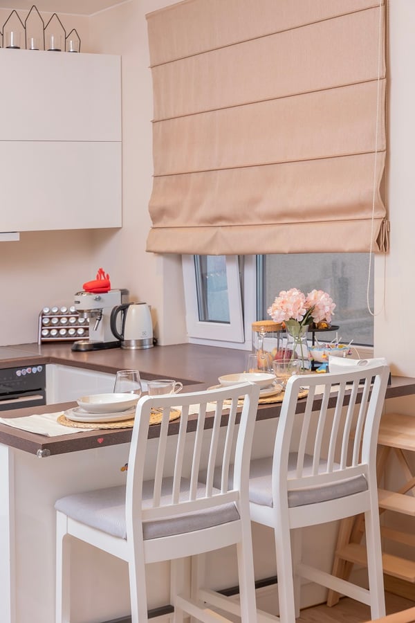 Close-up of kitchen bar counter with white chairs and table setting.