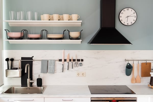 Close-up of kitchen countertop with hanging wooden utensils and modern coffee machine

